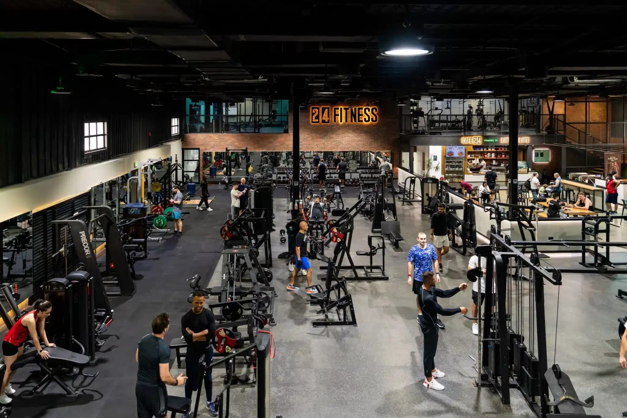 Busy 24 Fitness gym with people using weight machines, free weights, and cardio equipment